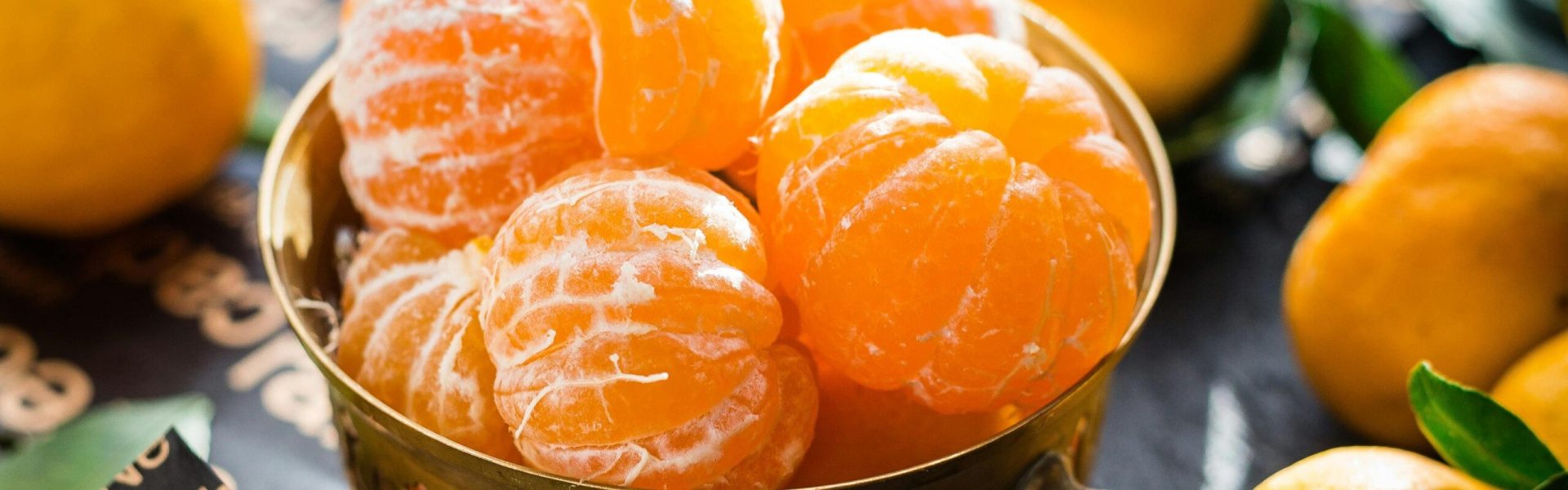 Vibrant peeled and whole tangerines in a rustic bowl highlighting freshness and health.